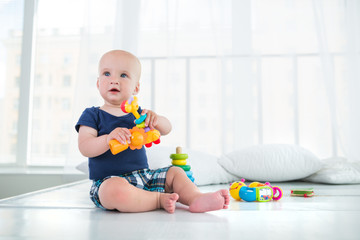 Charming little toddler boy playing with his favorite rattles in his room. The concept of a healthy and developed child in a complete family