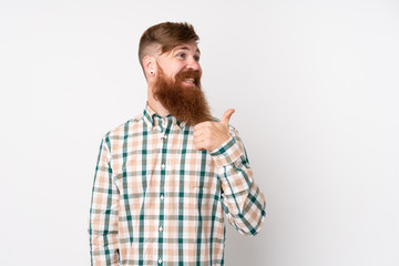 Redhead man with long beard over isolated white background pointing to the side to present a product