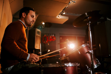 Musician playing drums, side view.