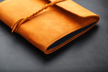 The leather cover of the album is made of brown handmade genuine leather on a black background. Elements of a leather product close-up.