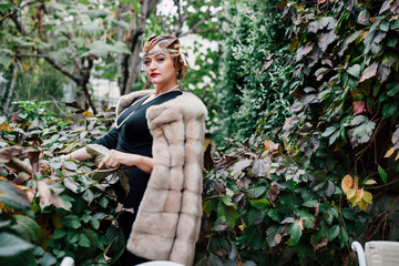 a gorgeous woman in a fur cape is surrounded by green ivy on her head a tiara, a bead hairstyle...
