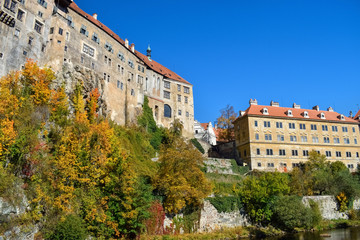 Fototapeta na wymiar Ancient buildings on the edge of a cliff with brown roofs and colored leaves on trees in Czech Republic in autumn