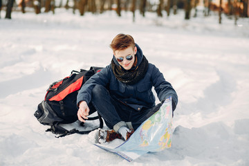 Fototapeta na wymiar young and handsome guy sitting in the winter snow-covered forest with map