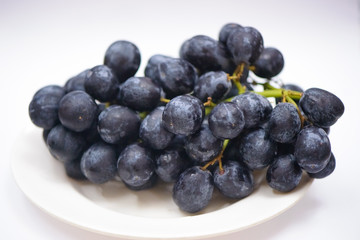 A bunch of black grapes isolated on a white background.