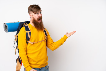 Young mountaineer man with a big backpack over isolated white background extending hands to the side for inviting to come