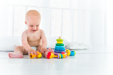 Charming cheerful kid in a diaper laughs and plays while sitting in his cozy room. The concept of a healthy happy baby and child care