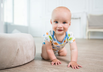 Portrait of a little happy baby crawling on the floor. The concept of a healthy developed child. Preparing for the first steps of the baby