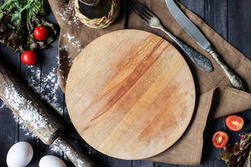 Concept of Italian and French cuisine on a dark wooden background. Lettuce, tomatoes, eggs and rolling pin. Background image, copy space © Nadia