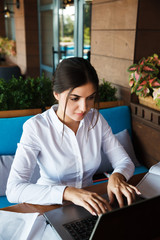 Successful happy young woman working on laptop in cafe outdoor. Portrait of smiling businesswoman