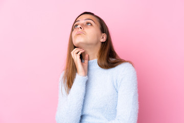 Teenager girl with blue sweater over isolated pink background thinking an idea