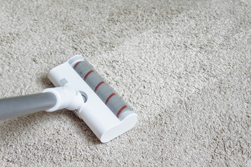 Vacuum cleaner head on dirty carpet with clean strip. Housework with using hoover. Turbo brush of...
