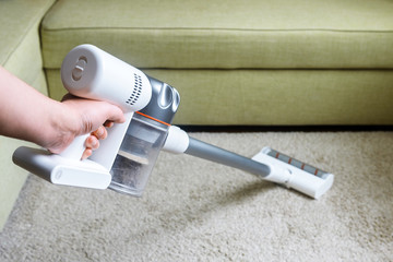 Wireless vacuum cleaner, stick hoover used on carpet in room at home