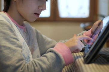 little girl writes with tablet