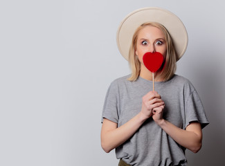 Beautiful blonde woman with heart shape candy on white background