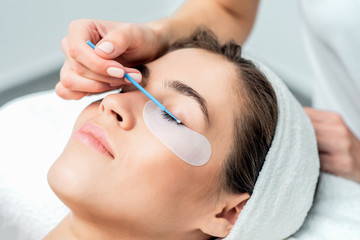 Beautiful woman receiving eyelash extension procedure, close up.