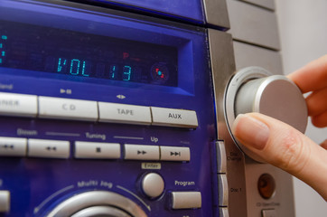 Manual volume control in the music center. A woman's hand adjusts the volume on the music center in...