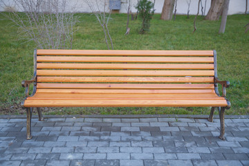 Wood exterior material. Wood material details. Blank Old bench in a shady area of the garden or the park,outdoor. Shaded wood park bench surrounded by greenery . Empty Park wooden bench Closeup view.
