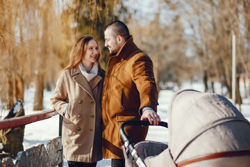 Elegant family in a winter forest. Mother with carriage. Man in a brown coat