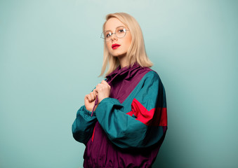 Beautiful woman in 90s sport suit in glasses on blue background
