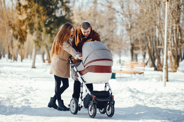 Fototapeta na wymiar Elegant family in a winter forest. Mother with carriage. Man in a brown coat