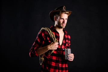 Sheriff concept. Brutal cowboy drinking alcohol. Western culture. Man wearing hat hold rope and...