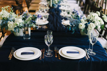  decor of a wedding table in dark blue color cards with names fresh flowers