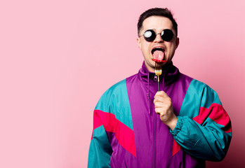Style guy in glasses with chili pepper on a fork on pink background