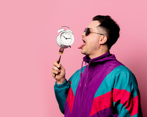 Style guy in 90s clothes with alarm clock on fork on pink background