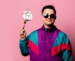 Style guy in 90s clothes with alarm clock on fork on pink background
