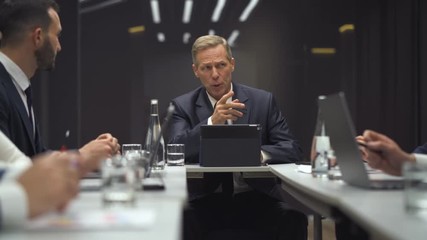 The businessman discusses something with partners at the meeting