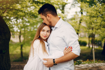 Cute couple in a park. Lady in a white dress. Guy in a white shirt