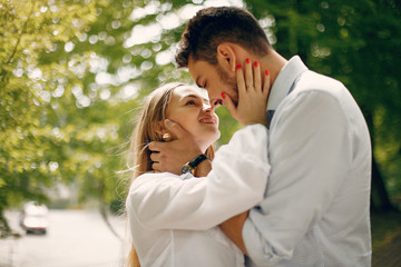 Fototapeta premium Cute couple in a park. Lady in a white dress. Guy in a white shirt