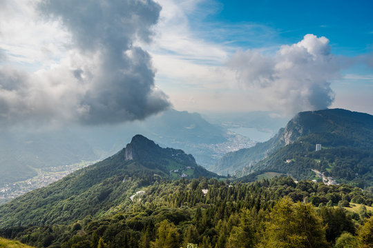 View from the mountain massif Grigna towards Lake Como, the town of Lecco and the surrounding mountains, covered by clouds and vapour from the lake. Hiking above Lake Como, Lombardy, Italy.