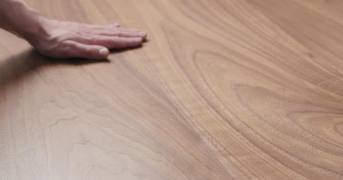 Slow motion man hand touches black walnut dining table surface