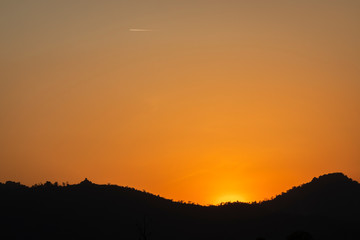 colorful sunset over mountain ridge with airplane flying on sky