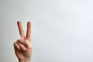 Two fingers up on the hand, peace symbol on a white background with a sweep for text