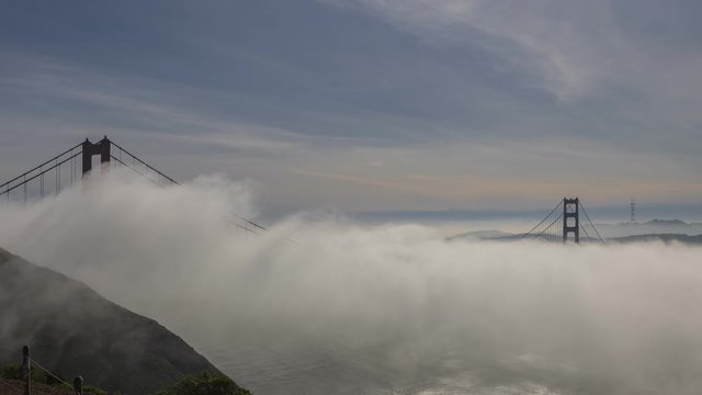 A time-lapse of the fog rolling under and over the Golden Gate Bridge showing the San Francisco skyline 
