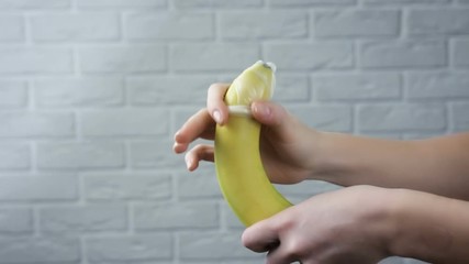 Woman putting condom on banana. Safe sex concept