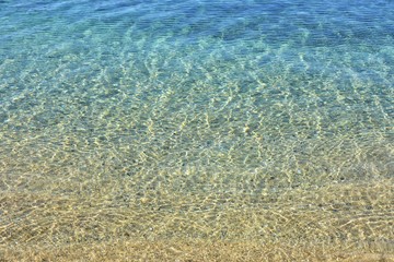 Fototapeta na wymiar Soft focus. Abstract water background. Clean transparent azure water backdrop. Pure sea with sun glare on the surface of water. Textured water surface with selective focus and sun beams. Summertime 