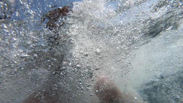 The guy dives into the water. A close-up of the diver&rsquo;s face, A young man swims underwater in the sea, On it is yellow-blue glasses for scuba diving, The sun's rays break through the water.