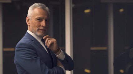 The handsome old businessman standing near the window. slow motion