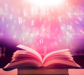 Open book on the table and English alphabet Floating above the book  in the library and blur bookshelf background