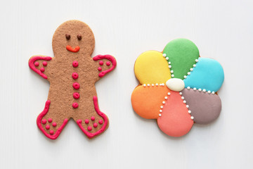 Gingery spice cookies in the form of man and flower with multicolored icing on the white wooden background