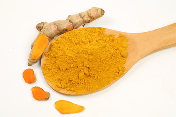 Turmeric powder in a wooden spoon and turmeric root extracted on a white background, used as a...