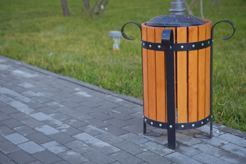 copy space on the left. Rubbish box in the park . A wooden urn and a comfortable empty park bench ....