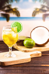 Glass of cold drink, with beach in the background. Refreshing drink, carioca mate tea, made in the city of Rio de Janeiro. Yerba mate drink, with coconut water and lemon. Brazilian summer tourism.