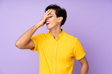 Man over isolated purple background smiling a lot