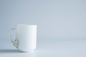 A white porcelain cup stands on a table. On white background