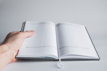 A book or notebook with blank blank pages in hand holds. On a white or gray background