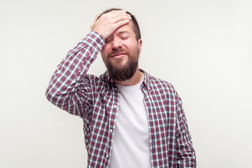 Bad memory. Portrait of forgetful embarrassed bearded man in casual plaid shirt making facepalm...